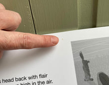 Load image into Gallery viewer, A close of of an example of ear and tear damage visible on some of the pages of the kamishibai. A finger points to a small mark on a page. Some text of the story is visible and the image of the hare covering its eyes.
