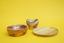 Load image into Gallery viewer, A wooden plate, a small wooden bowl and a medium sized wooden bowl on a yellow background.