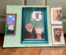 Load image into Gallery viewer, An A3 page from the story of the gingerbread man on a wooden floor with a green door in the background. The scene on the page is an art gallery featuring a man, a woman, a gingerbread man and a hare in photo frames. 
