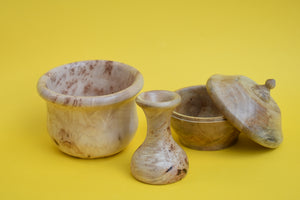 A wooden bowl, a wooden vase and a wooden pot with it's lid resting on it's side on a yellow background.
