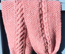 Load image into Gallery viewer, A close up of a hand knitted pink scarf which has a cable pattern. 
