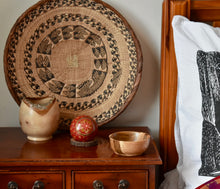 Load image into Gallery viewer, Three hand turned wooden bowls. The smallest bowl has a red wooden ball sitting in it. They are on a bedside table. The edge of a black and white pillow can be seen and there is a large round African basket propped against the wall in the background. 
