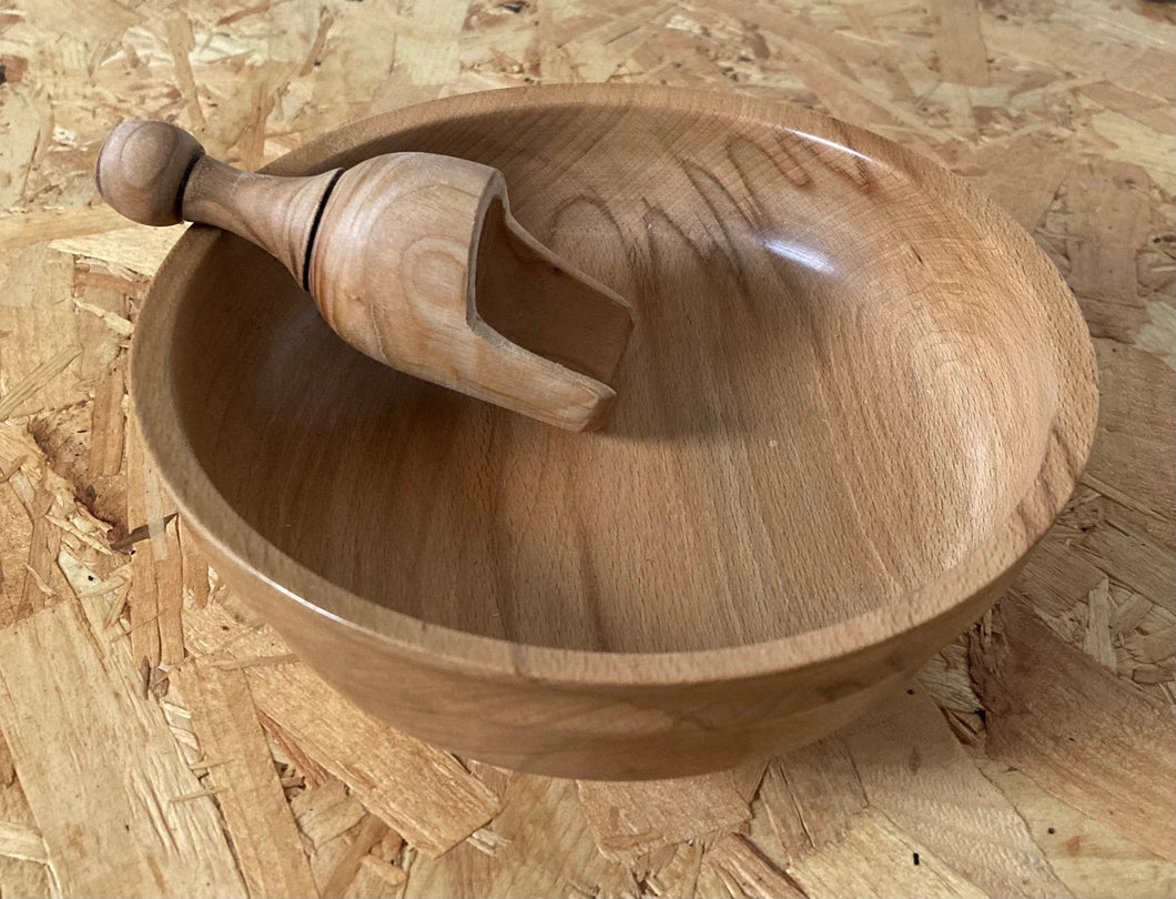 A wooden bowl on a USB table with a wooden scoop inside the bowl. 