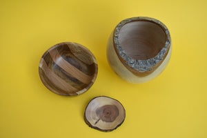 An overhead shot of three different sized hand turned wooden bowls on a yellow background