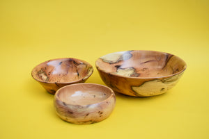 Three wooden bowls of different sizes on a yellow background. 