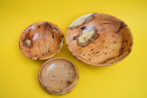 A birds eye view of three wooden bowls of different sizes on a yellow background.