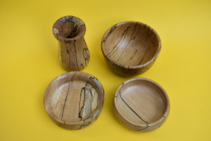 Birds eye view of four hand-turned beautiful bowls with a uniques pattern on a yellow background. 