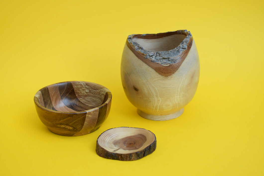 Three different sized hand turned wooden bowls on a yellow background