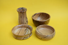 Load image into Gallery viewer, Four hand-turned wooden items. Three bowls and one vase. There is a yellow background. 
